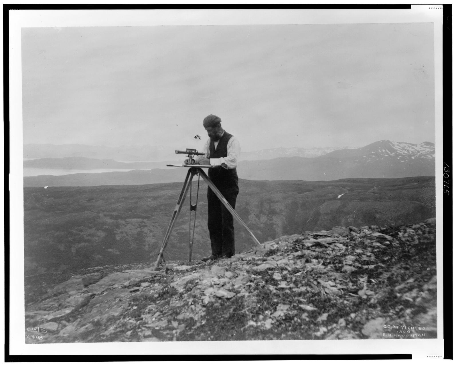 Surveyor with a theodolite on a mountain ridge, 1899