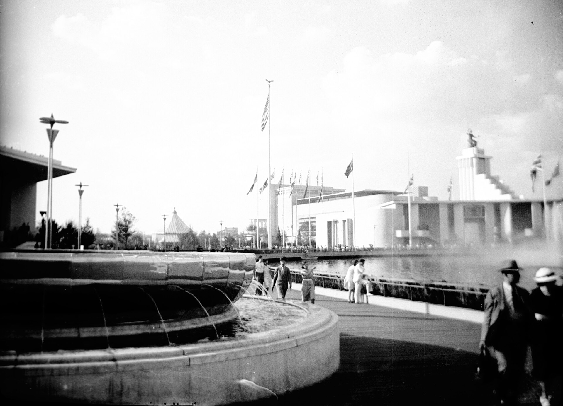 Visitors beside a pool at the 1939 New York World's Fair, with white modern pavilions behind