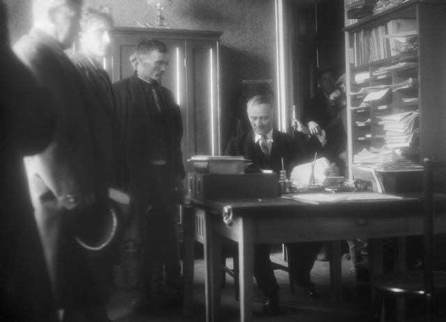 Job seekers standing at a desk in the Oulu employment office in 1931, a clerk writing in the files