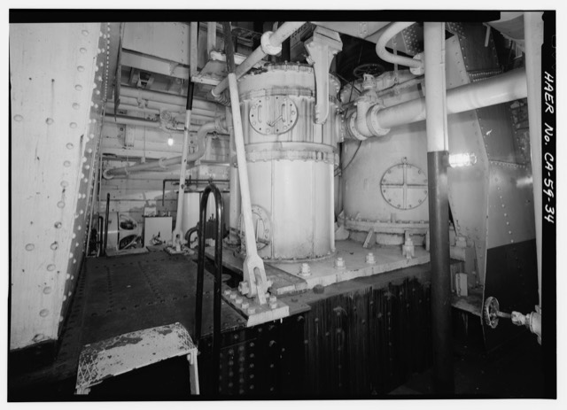 The engine room of a steam ferry, with a large pump, pipes and gauges