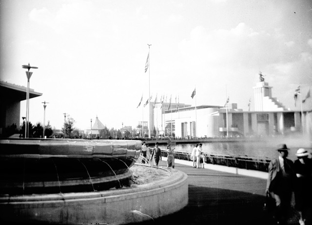 Visitors beside a pool at the 1939 New York World's Fair, with white modern pavilions behind