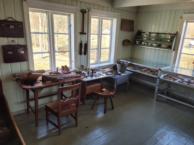 A small shoemaker's workshop with a workbench, tools and shoes on the shelves