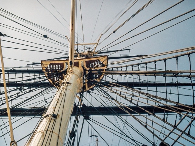 Looking up a sailing ship mast at the rigging and ropes spreading out against the sky