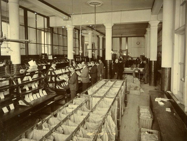 The mail sorting room of the General Post Office in Wellington in the early 1900s, with sorting frames and sacks