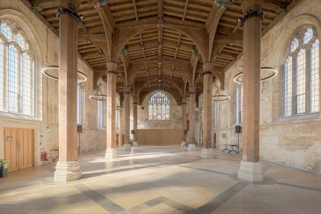The empty main hall of the York Guildhall, with stone pillars and a timber roof